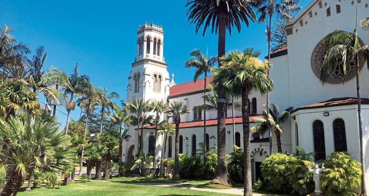 Church with palm trees in a lush garden setting.