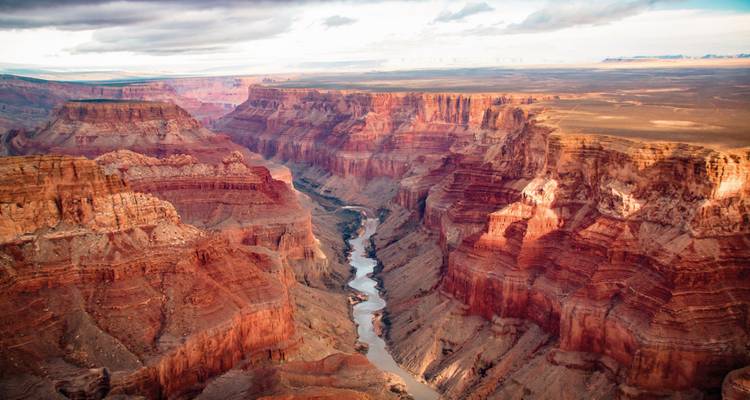 Las enormes paredes de roca roja en múltiples capas se desploman hacia el sinuoso río Colorado en el Gran Cañón.