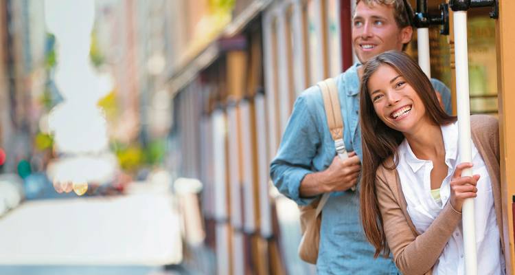 Smiling couple on a streetcar in an urban setting.