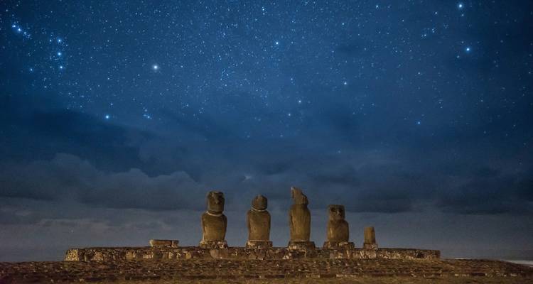 Moai statues under a starry night sky.