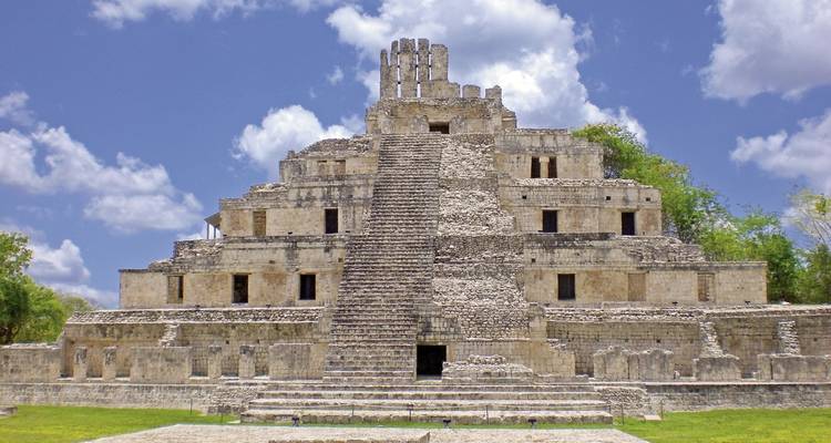 Une ancienne pyramide maya sous un ciel bleu avec des nuages.
