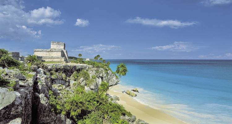 A stone structure on a cliff by the turquoise ocean.