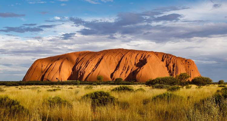 Majestischer Uluru-Felsen unter einem teilweise bewölkten Himmel.