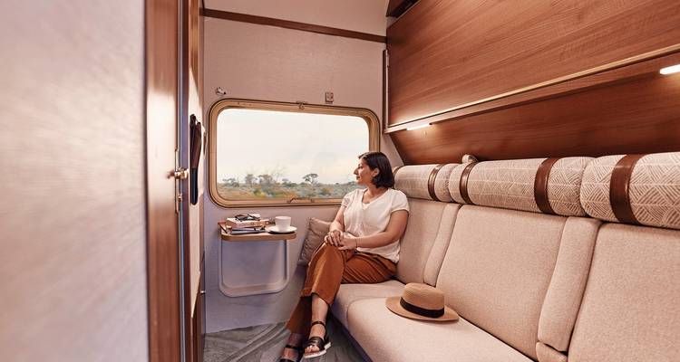 Femme assise dans un wagon de train regardant par la fenêtre.