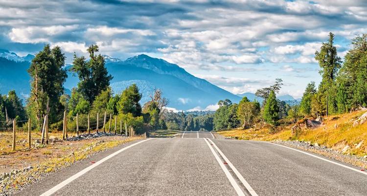 Open road leading to mountains and forests.