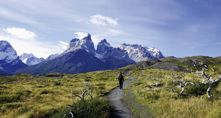 Trekker walking towards majestic mountains.