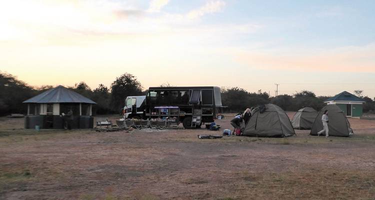 Campingplatz mit Zelten und einem Lastwagen während der Dämmerung.