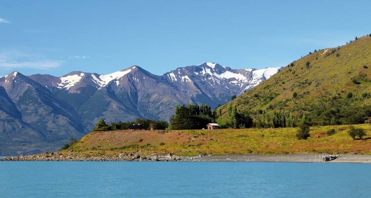 Vue pittoresque de montagnes et d'un lac paisible avec une petite maison.