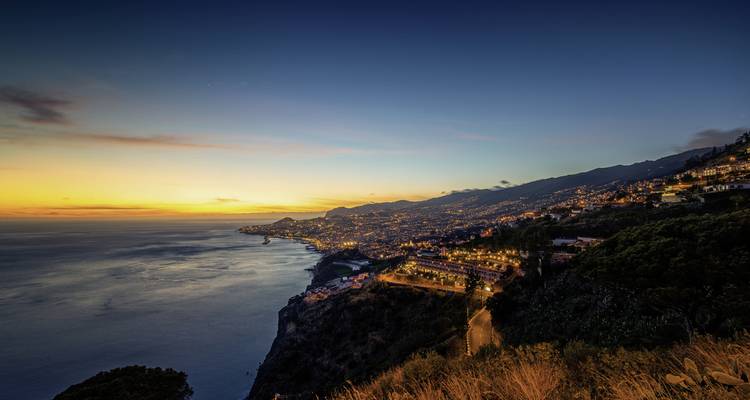Littoral éclairé par les lumières de la ville pendant le coucher de soleil.