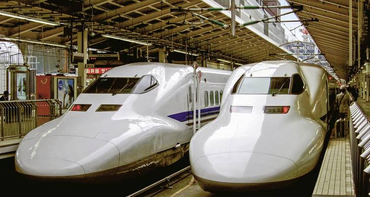 Deux trains shinkansen modernes garés sur un quai de gare.