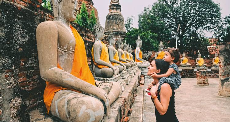Une femme et un enfant admirant d'anciennes statues de Bouddha en pierre.