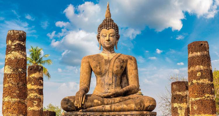 Große steinerne Buddha-Statue, die im Freien unter blauem Himmel sitzt.