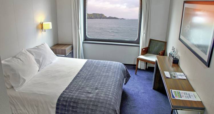 Intérieur de cabine de navire avec lit et vue par la fenêtre sur l'océan.