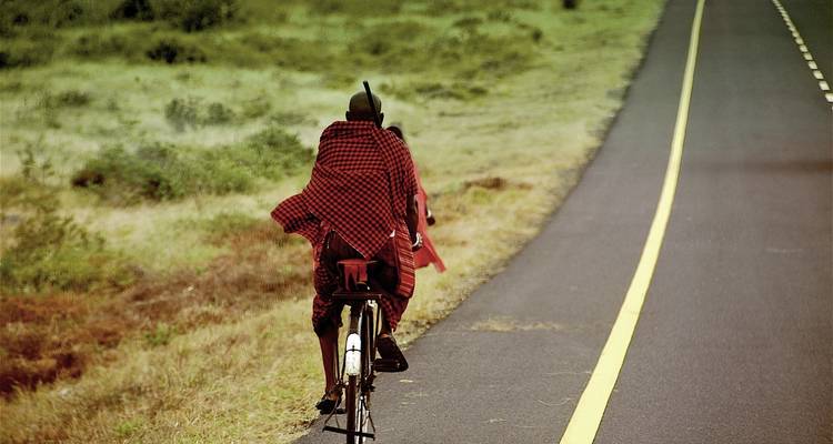 Persoon die fietst op een weg door grasland.