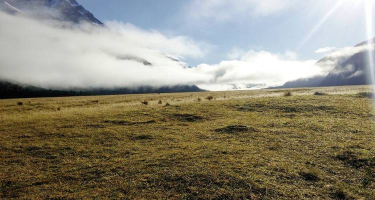 Vaste champ ouvert avec des nuages bas et des rayons de soleil qui percent à travers.