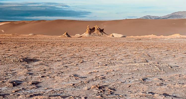 Woestijnlandschap met grote zandduinen en kale grond.