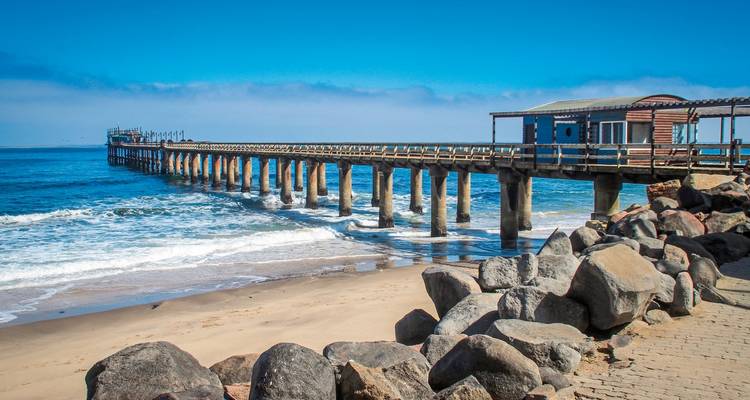 Pier die zich uitstrekt in de oceaan met rotsen op de kust.