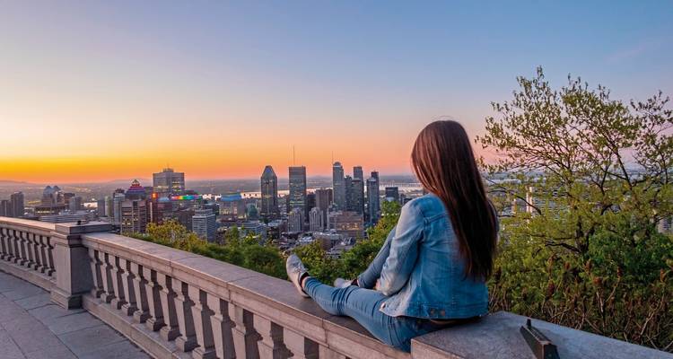 Una persona sentada en una terraza con vista al horizonte de la ciudad al atardecer.