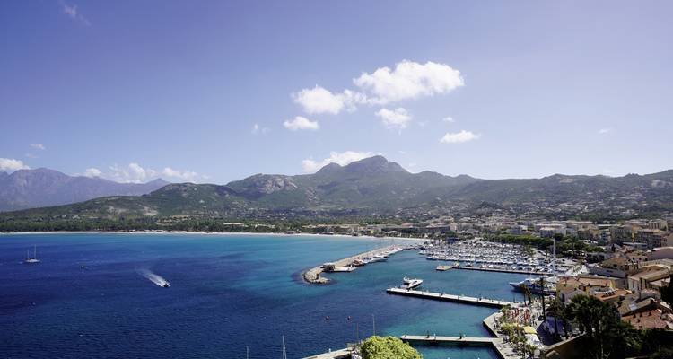 Vue aérienne d'un port de plaisance avec des montagnes en arrière-plan.