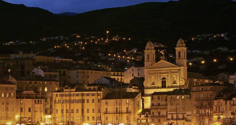 Bâtiments historiques et une église, illuminés la nuit.