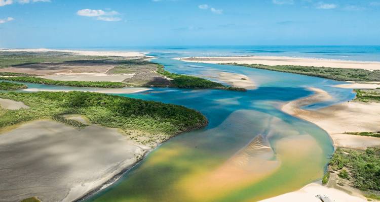 Vue aérienne d'une rivière coulant à travers un paysage sablonneux.