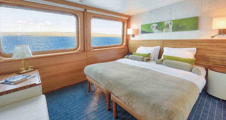 Innenraum einer gemütlichen Hütte mit Blick auf das Meer durch große Fenster.