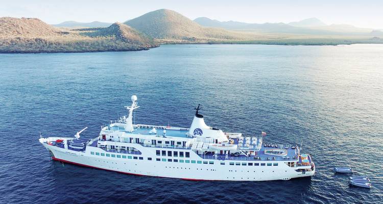 Großes Kreuzfahrtschiff schwimmt nahe Inseln mit Bergen im Hintergrund.
