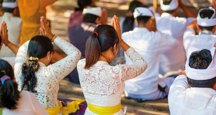 Des personnes participant à un rituel traditionnel, assises et les mains levées.