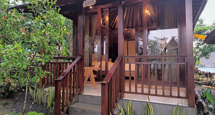 Extérieur d'une cabane en bois avec de grandes portes vitrées et un environnement verdoyant.
