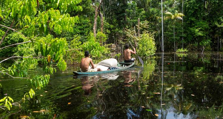 Zwei Menschen fahren Kanu in einem überfluteten Wald