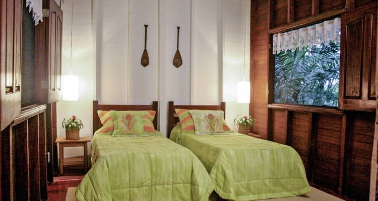 Rustiek hutinterieur met twee eenpersoonsbedden en decoratieve elementen.