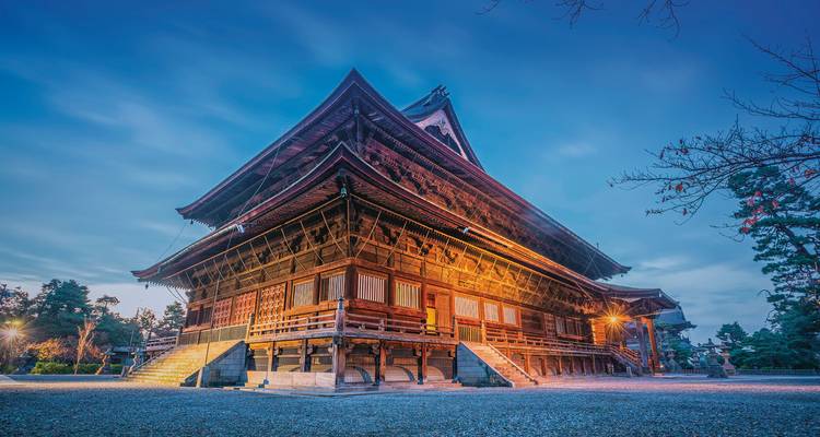 Temple traditionnel illuminé la nuit avec un ciel bleu.