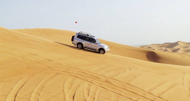 Geländewagen fährt auf Wüstensanddünen.