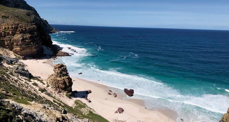 Coastal view of a sandy beach with waves hitting the shore.