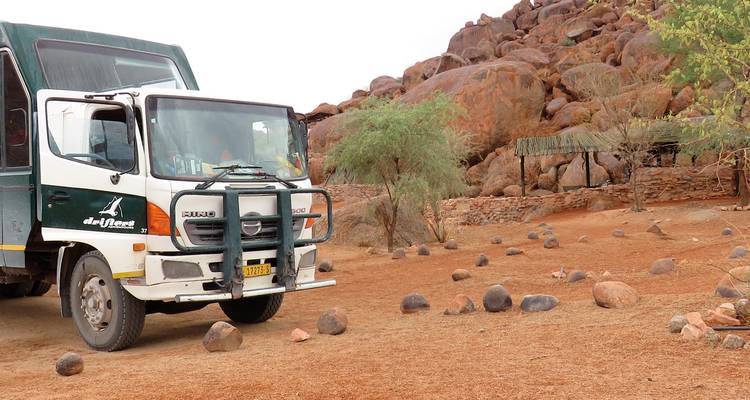 Camion de tournée garé à côté d'un terrain rocheux.