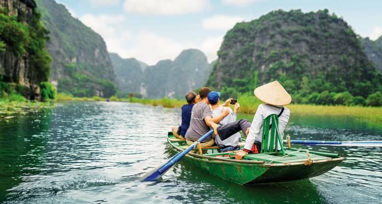 Toeristen in een boottocht langs de rivier met karstbergen op de achtergrond.