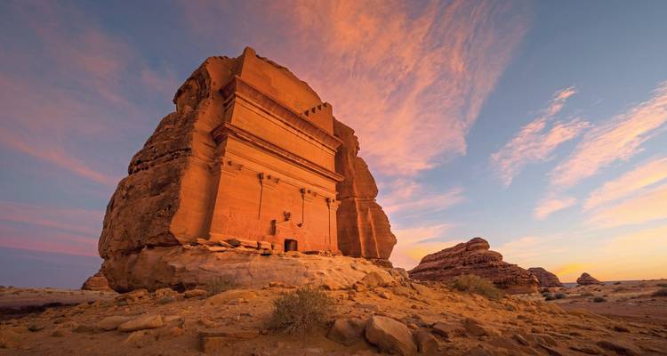 A monumental rock tomb lit by the setting sun.