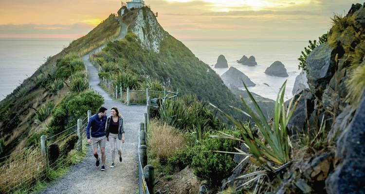 Couple faisant de la randonnée sur un sentier côtier au coucher du soleil.