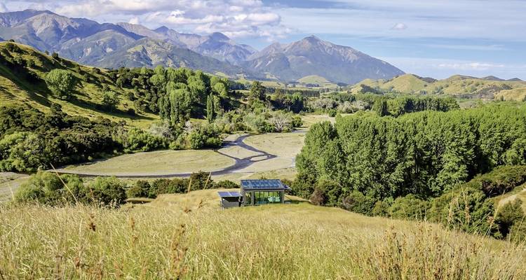 Rustikale Landschaft mit einer modernen Hütte und fernen Bergen.