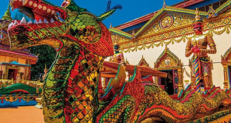 Vibrant dragon sculpture in front of an ornate temple.