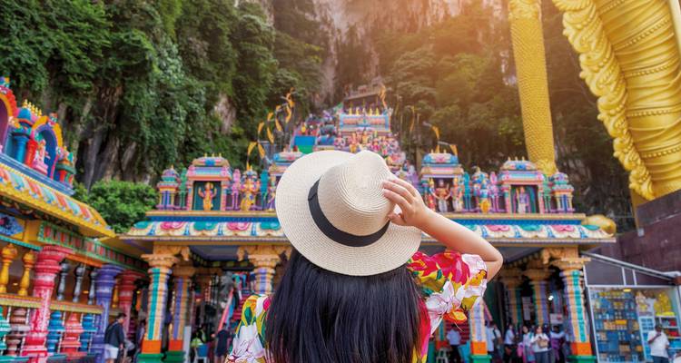 Woman in a hat observing colorful temple facade.