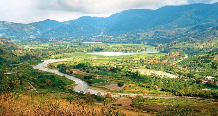 Uitgestrekt uitzicht over dal met kronkelende rivier en bergen.
