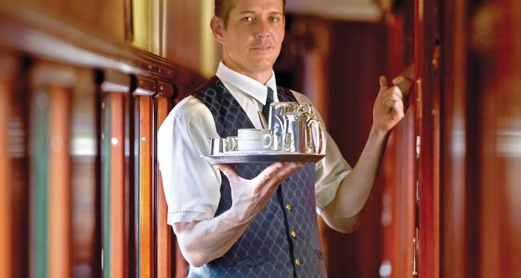 Contrôleur de train portant un plateau de boissons.