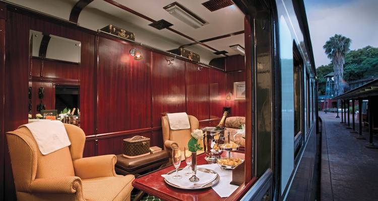 Elegante Zugwaggon-Suite mit Sesseln und einem Essbereich.