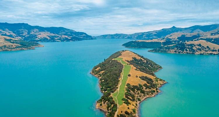 Peninsula surrounded by turquoise waters and hills.