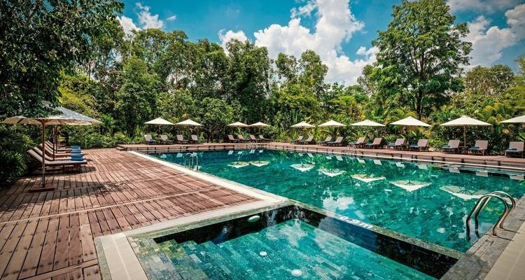Outdoor swimming pool surrounded by sunbeds and umbrellas.