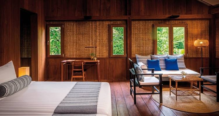 Cozy wooden cabin interior with a bed and seating area.