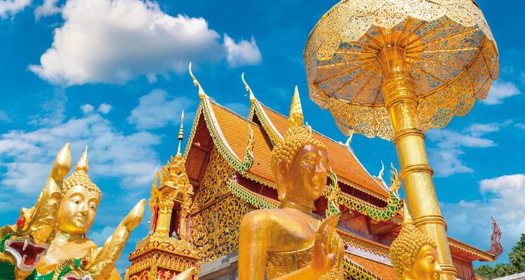 Statues dorées et un temple orné coloré avec un ciel bleu en arrière-plan.