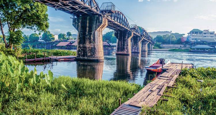 Grand pont historique traversant une rivière avec de la végétation le long des berges.