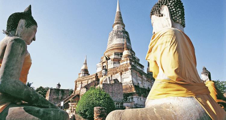 Statues bouddhistes dans un temple avec une pagode en arrière-plan sous un ciel dégagé.